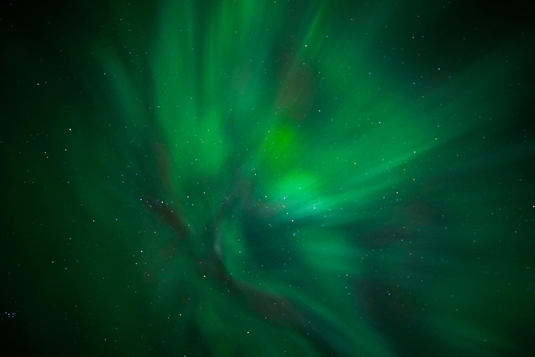 Green aurora corona spiralling directly overhead in a star filled sky